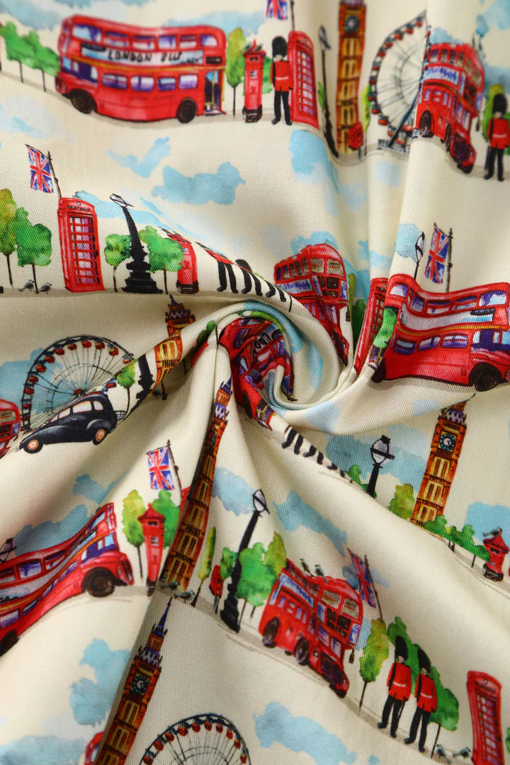 Fabric of vintage-style dress with London-themed design featuring double-decker buses, red telephone boxes, and the Big Ben clock tower.