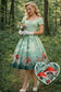 Woman in a vintage-style dress with mushroom and fairy land design, standing in a forest